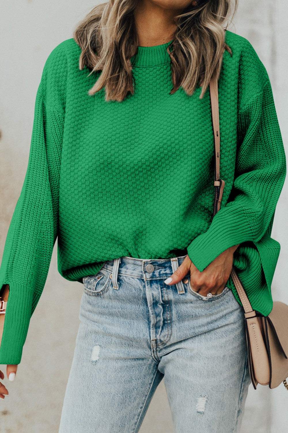 Textured green round neck long sleeve sweater with slit detail, worn with light blue jeans.