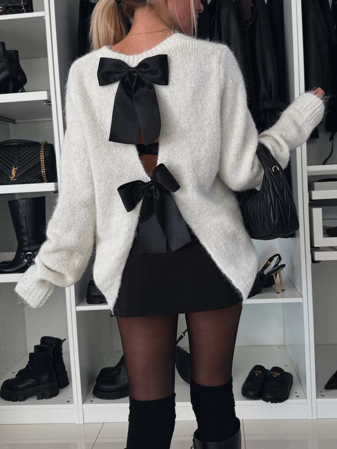 Bow slit back round neck sweater with black bow accents and slightly stretchy acrylic material.