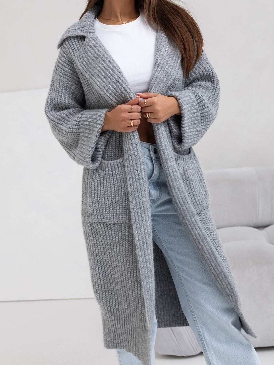 woman wearing gray pocketed collared neck dropped shoulder cardigan with moderate stretch over white top and light blue jeans