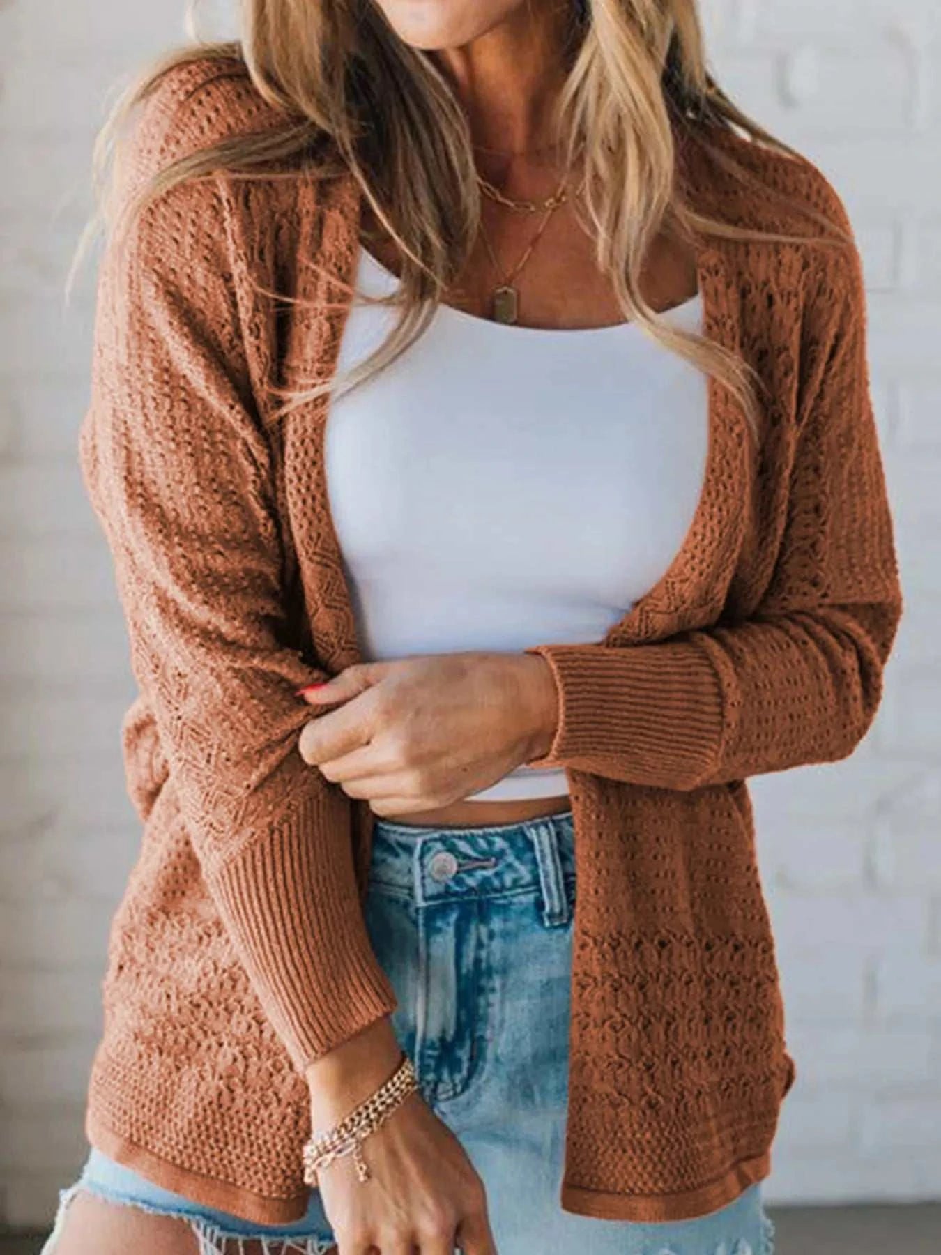 Brown open front knitted cardigan with eyelet details worn over white tank top and blue denim jeans
