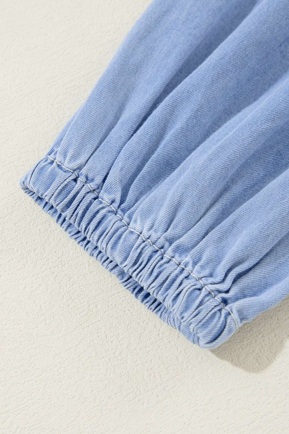 Close-up of a blue sleeve with ruffled elastic hem, part of a V-neck tiered mini dress.