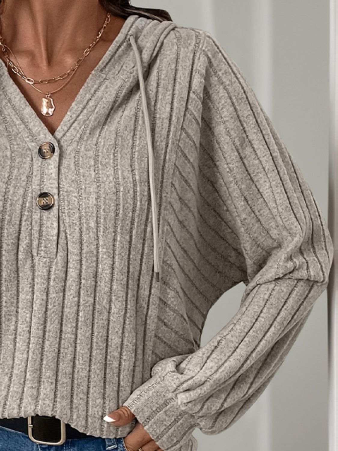 Gray drawstring long sleeve hoodie with button details and ribbed texture.