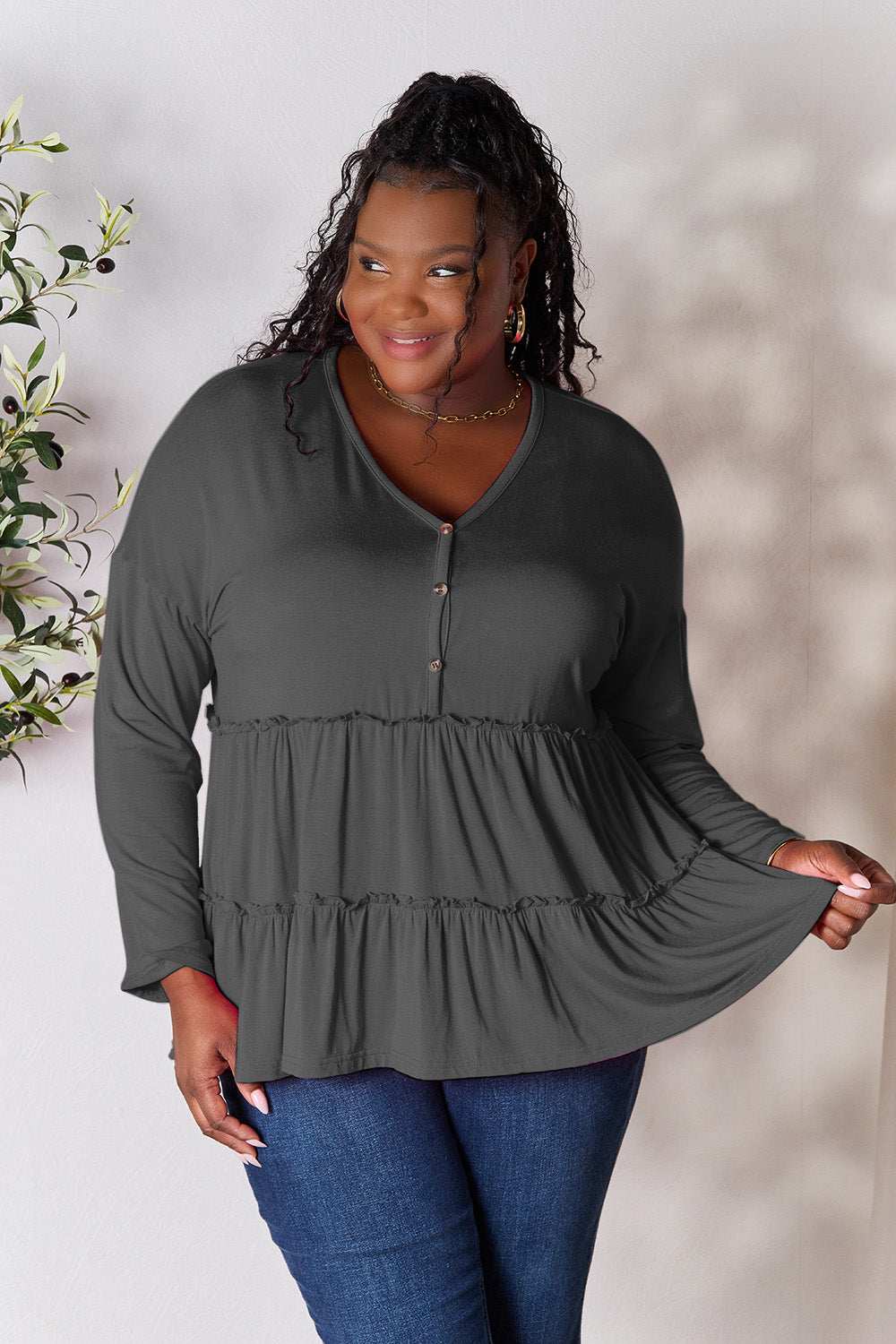 Half button long sleeve ruffle hem blouse in gray, worn by model; buttoned and slightly stretchy.