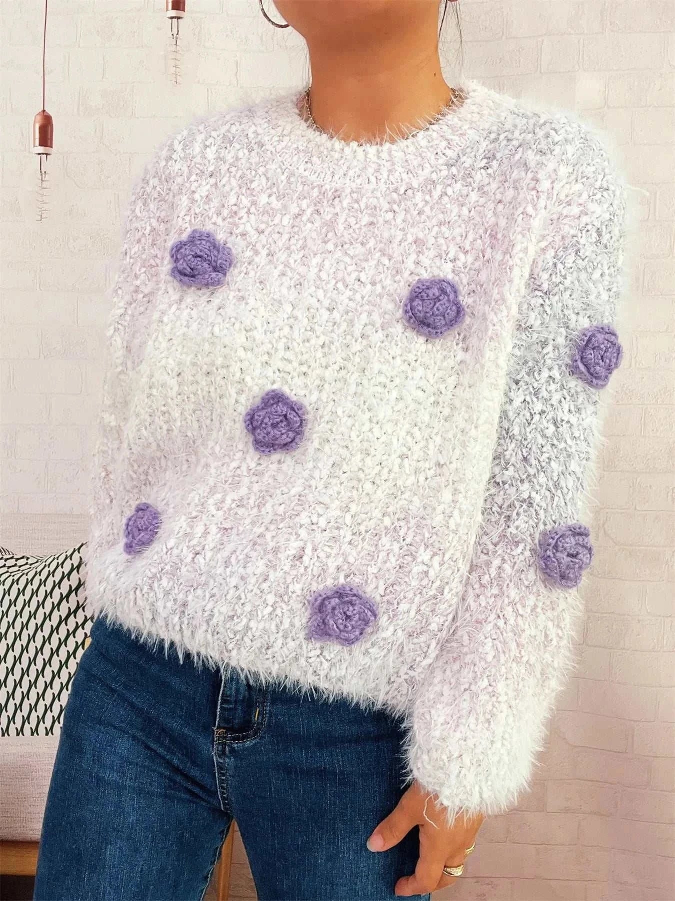 White oversized fuzzy round neck sweater with purple flower embellishments and long sleeves