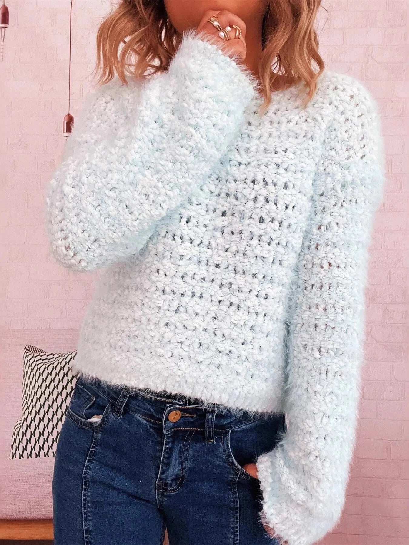 Woman wearing a light blue crochet round neck dropped shoulder sweater with long sleeves and slightly stretchy fabric.