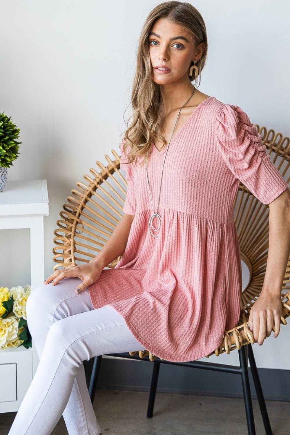 Heimish full size waffle knit V-neck babydoll top in pink on woman sitting.
