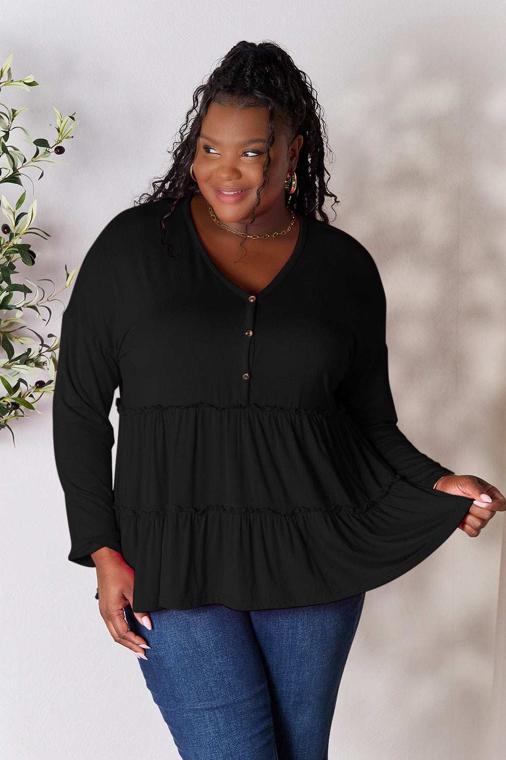 Half button long sleeve ruffle hem blouse in black, featuring a buttoned and ruffled design, slightly stretchy material.