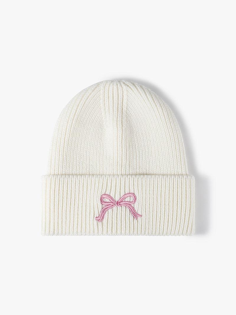 White knit hat with pink embroidered bow design.