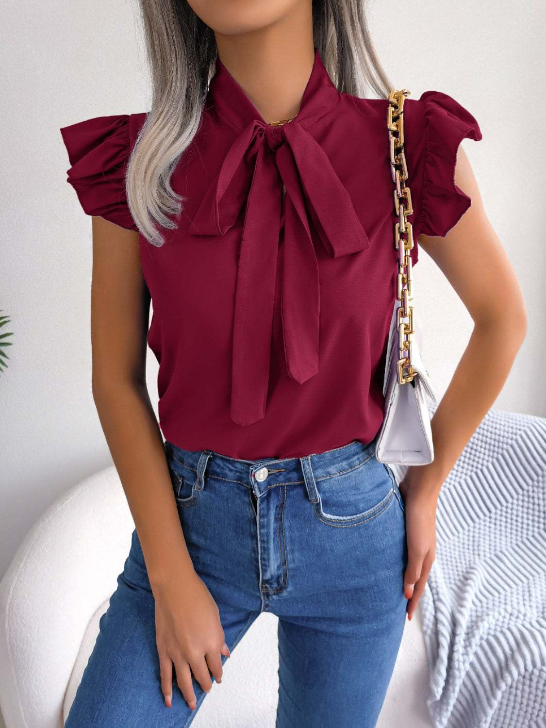 Tie neck cap sleeve blouse in deep red with slightly stretchy material.