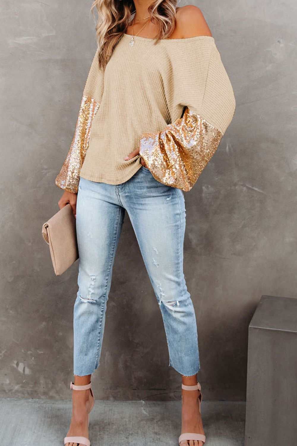 Sequin waffle-knit blouse with shimmering sleeves, worn with light blue jeans.
