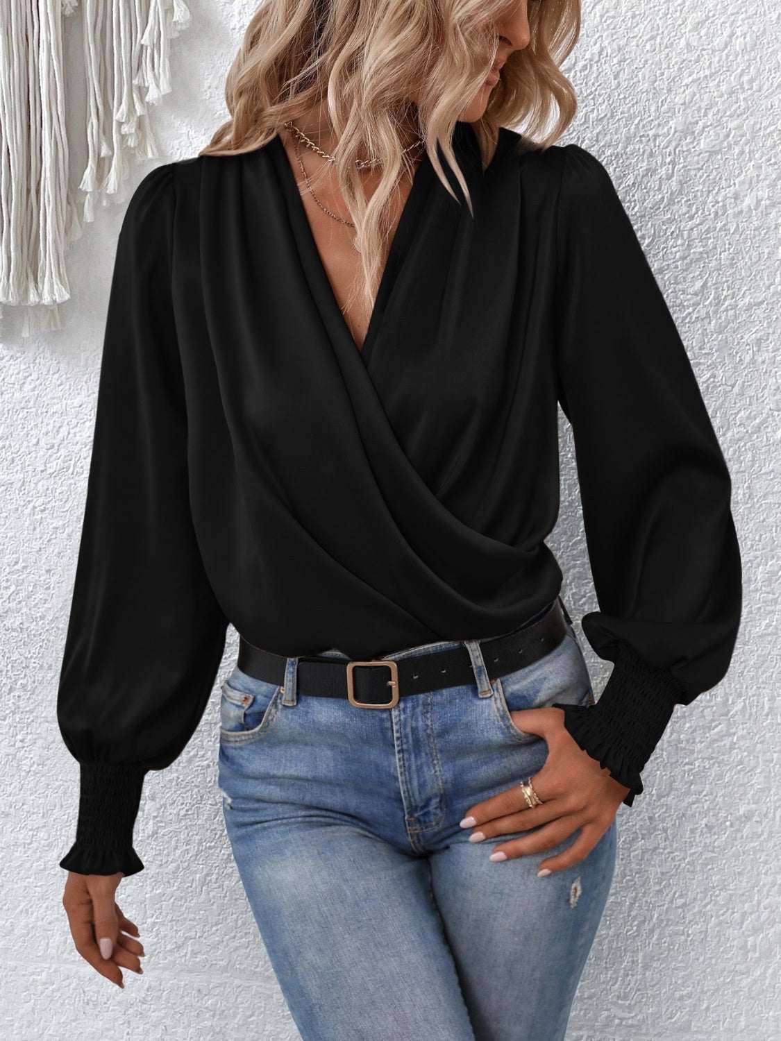 Surplice smocked lantern sleeve blouse in black, styled with denim jeans.