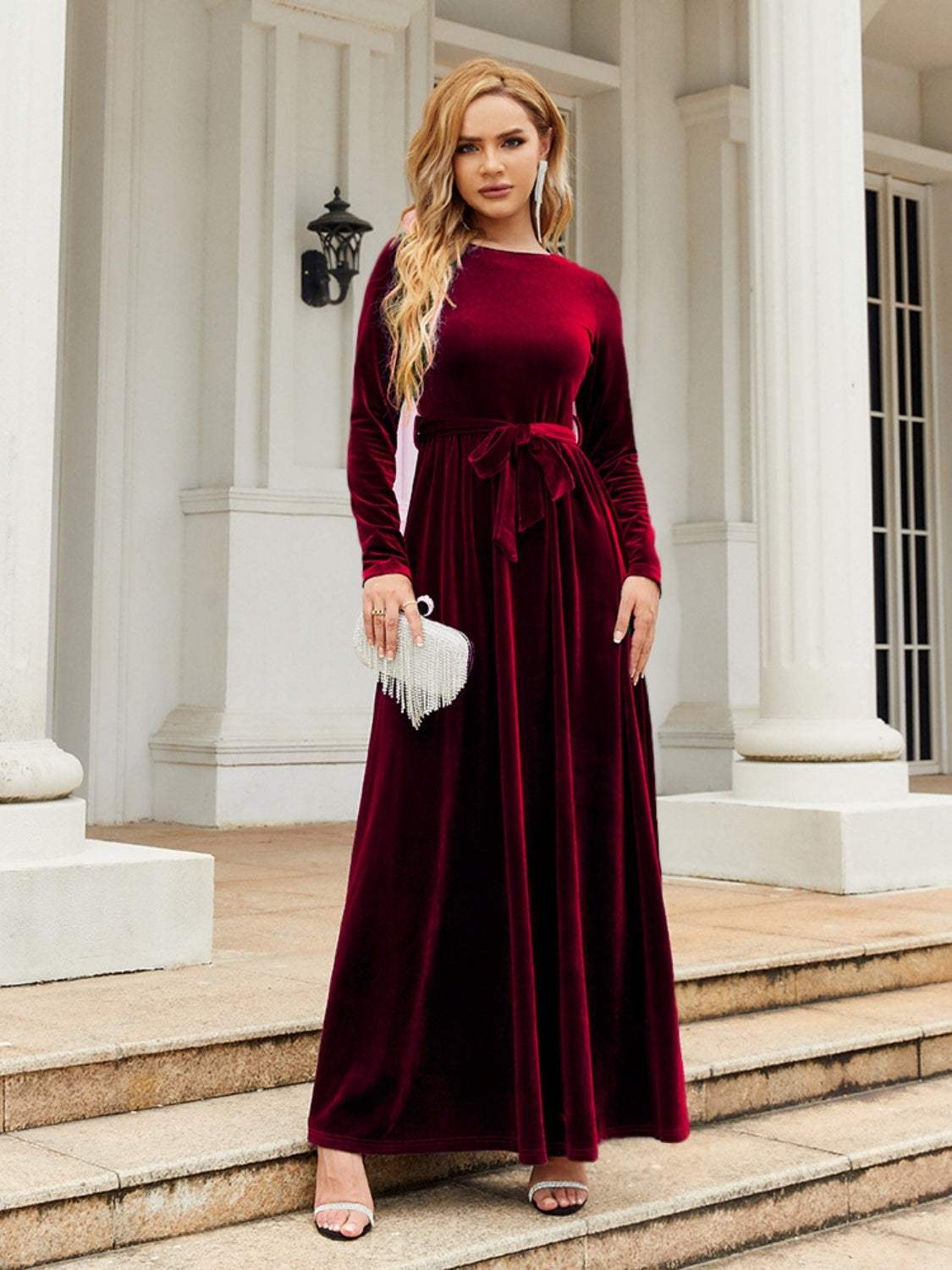 Tie front round neck long sleeve maxi dress in deep red, polyester, slightly stretchy, worn by a woman standing on stairs.
