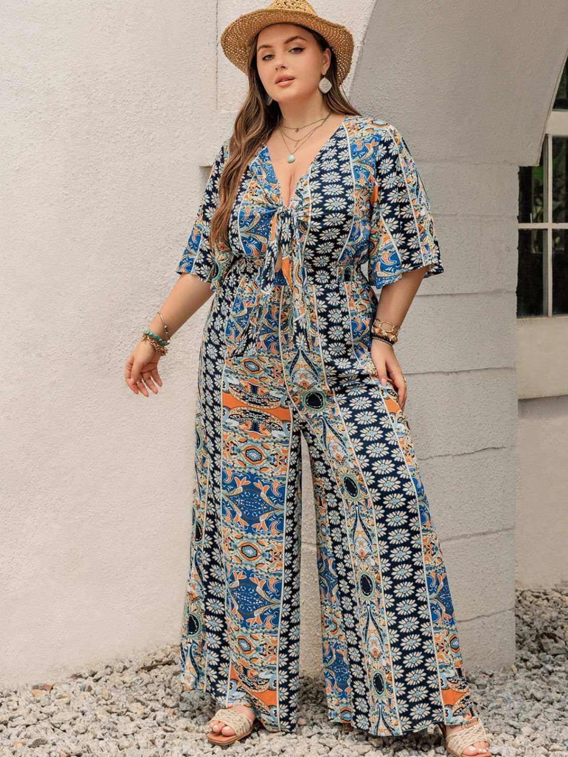 Plus size printed half sleeve wide leg jumpsuit with tied waist and colorful pattern.