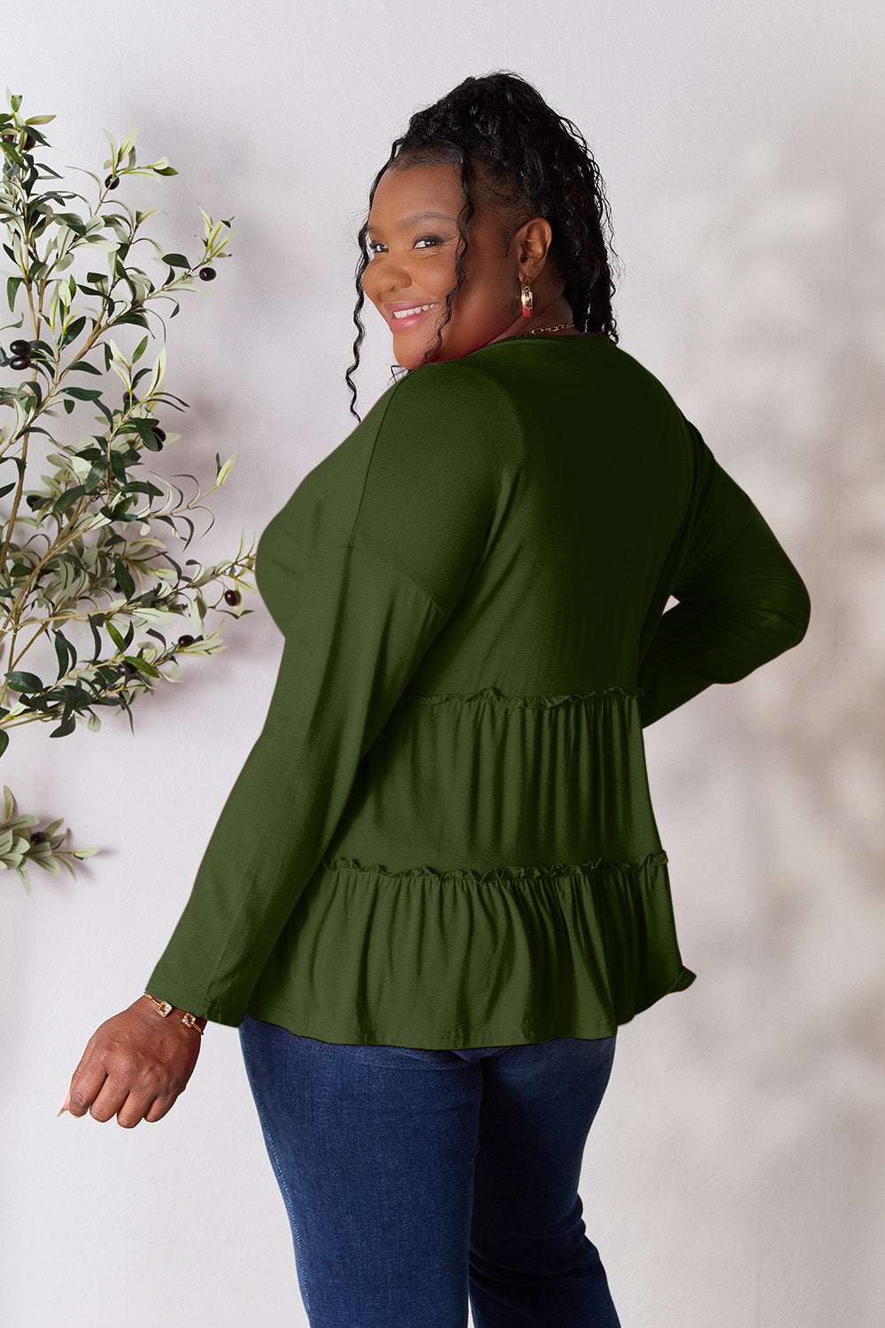 Ruffle hem blouse with long sleeves and half button design in green, shown on model.