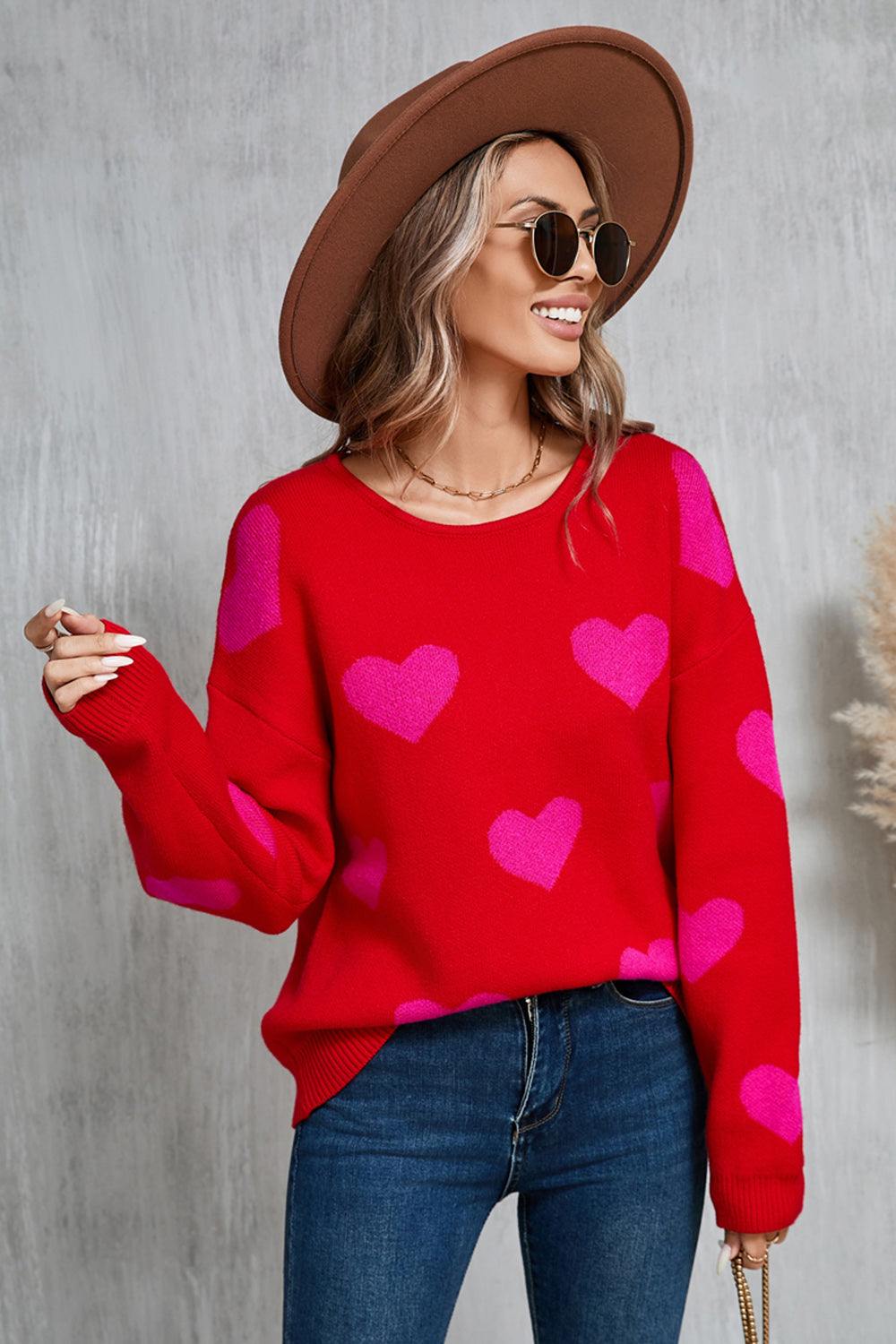 Woman wearing red sweater with pink heart pattern, round neck, and dropped shoulders.