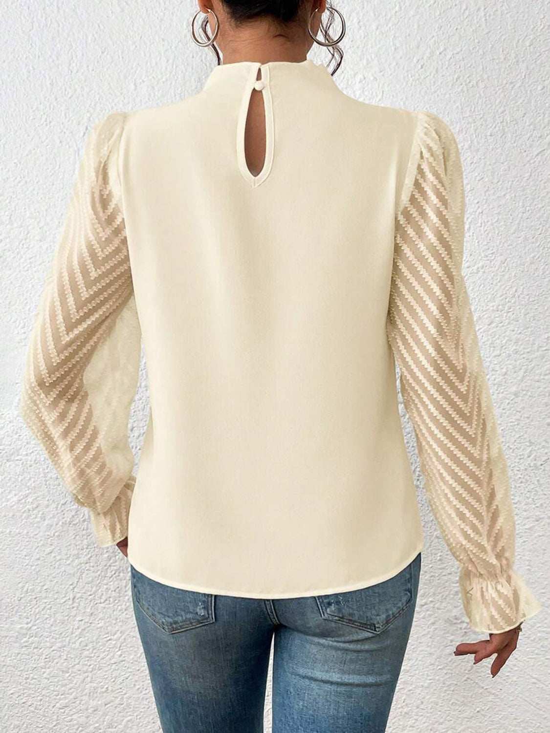 Mock neck flounce sleeve blouse with ruffled details and semi-sheer sleeves.