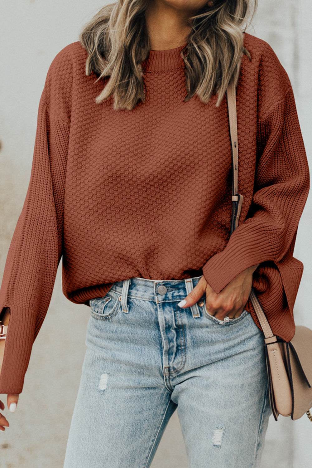 Textured round neck long sleeve sweater worn with jeans.