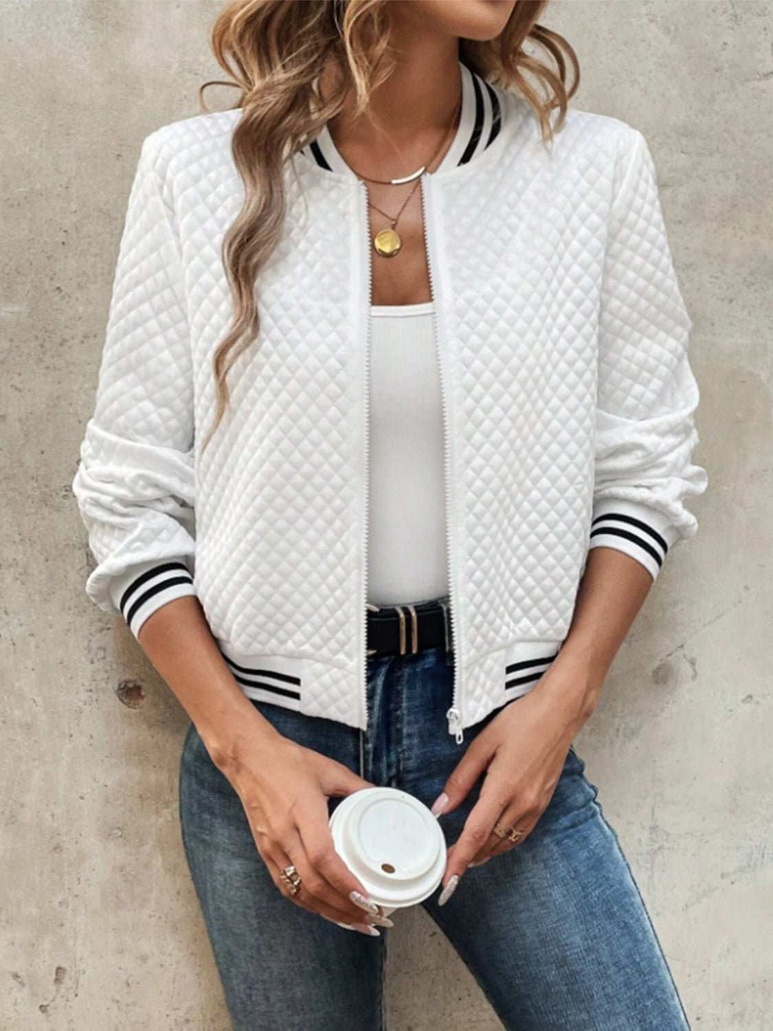 White quilted zip up long sleeve jacket with striped cuffs and collar worn with white top and jeans