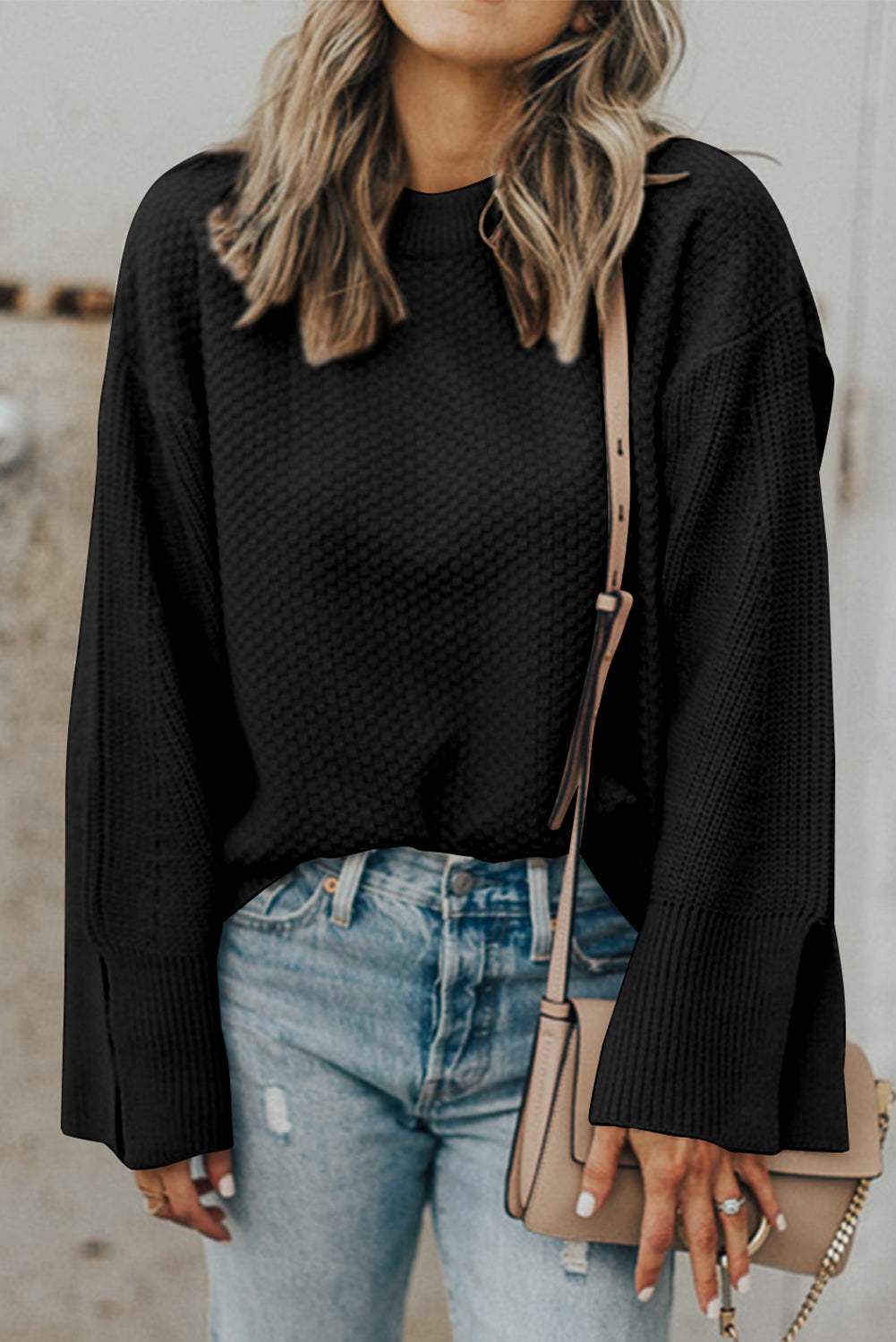 Textured round neck long sleeve sweater with slit detail, worn with blue jeans.