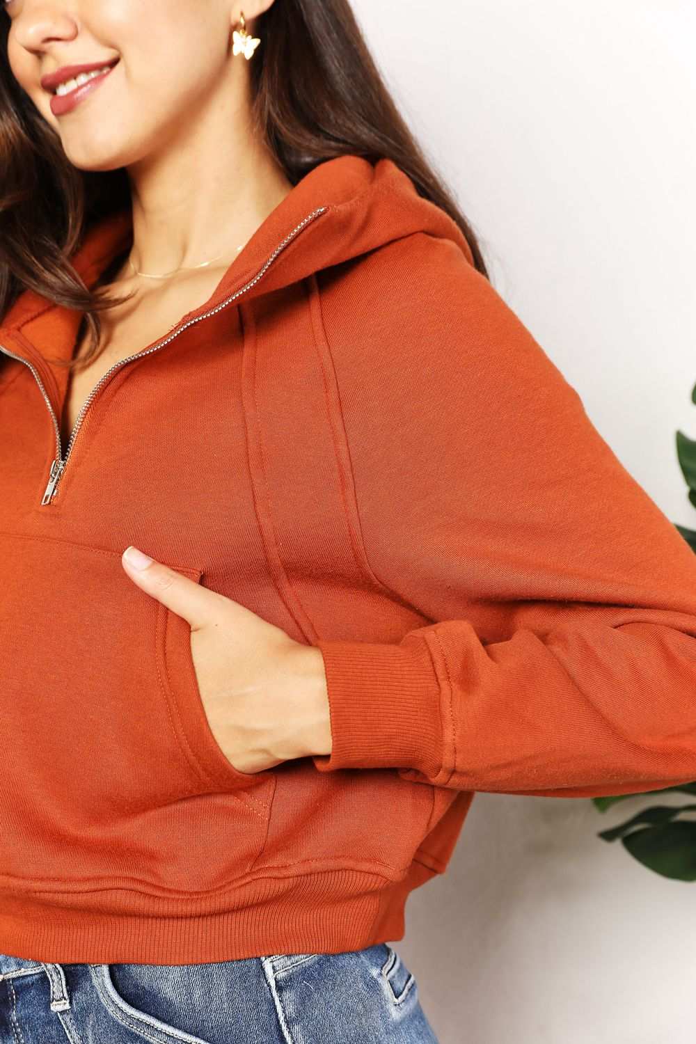 Solid-colored cropped hoodie with half-zip and long raglan sleeves.