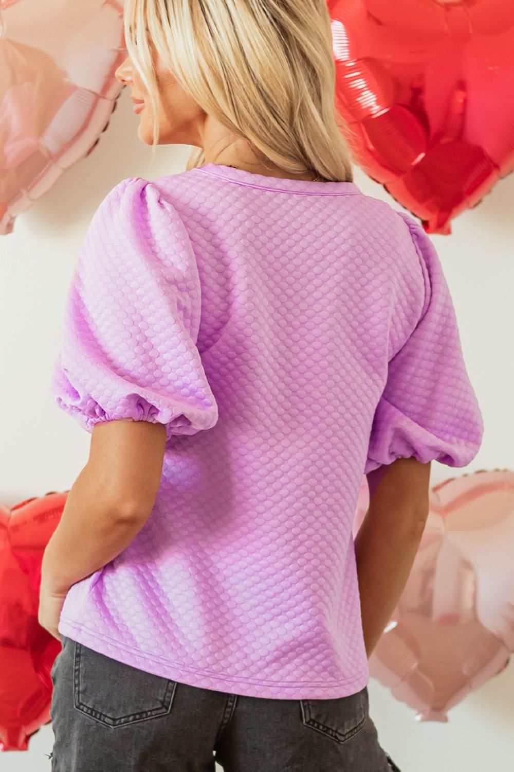 Textured round neck puff sleeve blouse in light purple worn by a woman, showcasing back and sleeve detail.