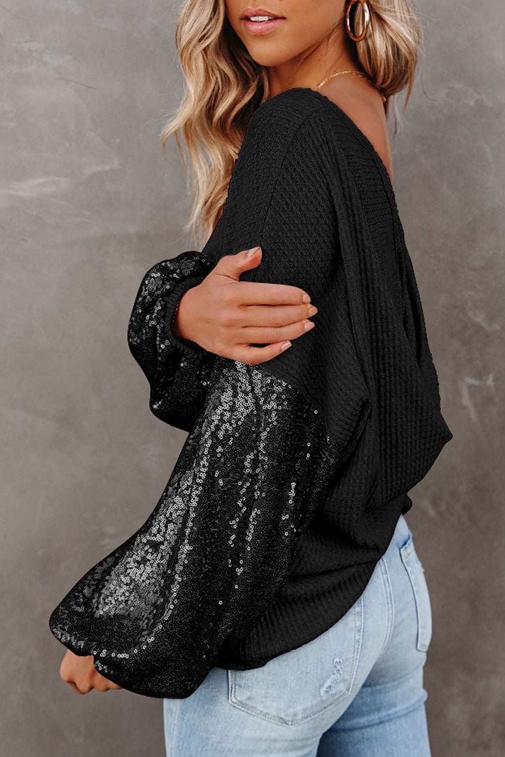 Sequin waffle-knit blouse with black sequined sleeves, waffle texture, and relaxed fit.