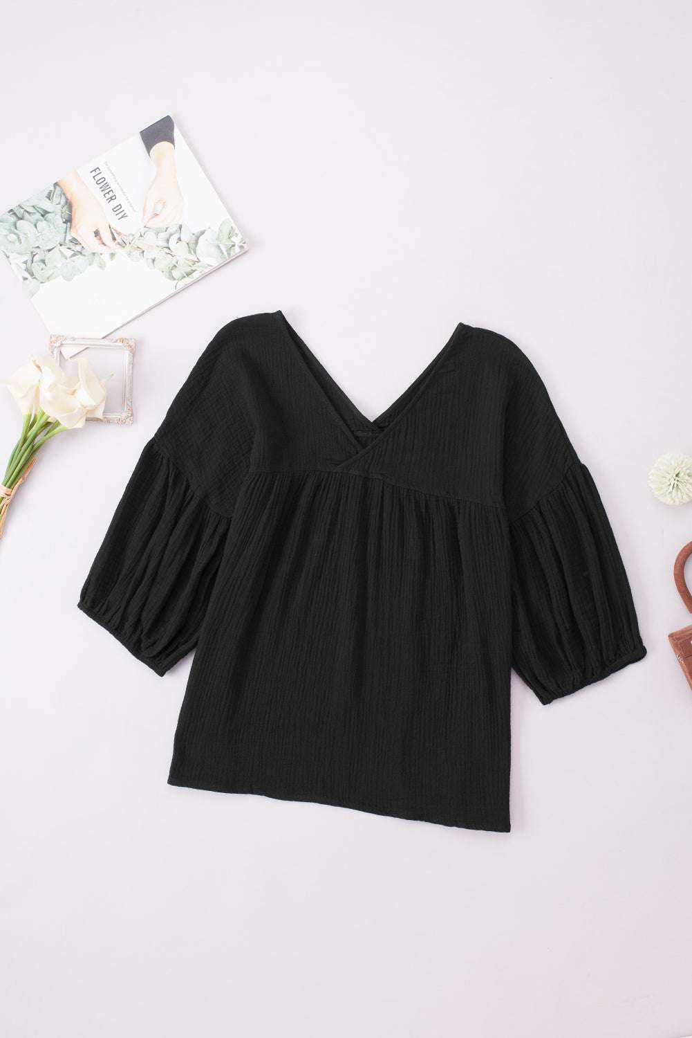 Black dropped shoulder V-neck blouse with long sleeves and casual style.