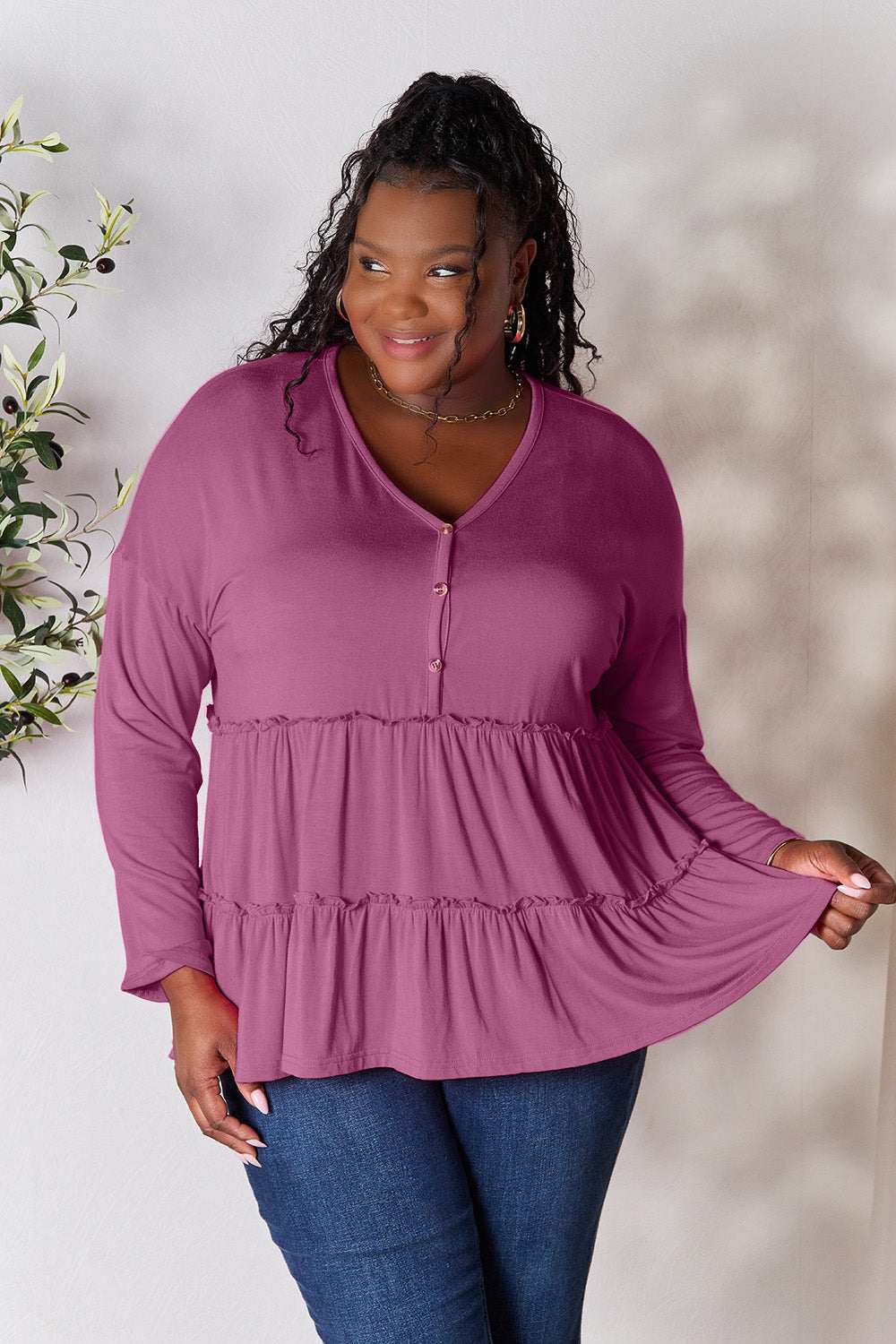 Half button long sleeve ruffle hem blouse in purple, worn by a model, features buttoned detail and slight stretch.