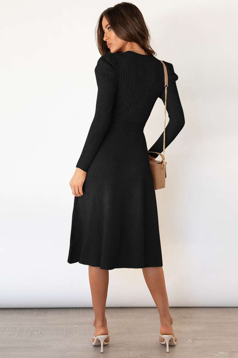 Round neck long sleeve tie waist sweater dress in black worn by a woman.