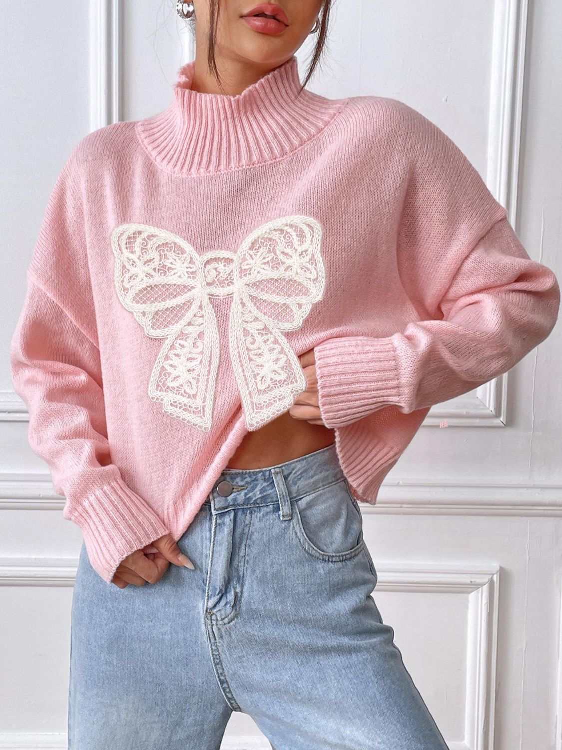 Pink bow turtleneck long sleeve sweater with white lace bow design.