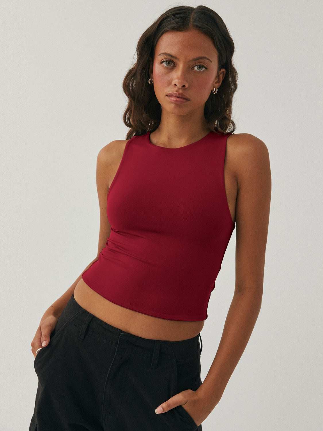 Woman wearing a round neck cropped tank in red.
