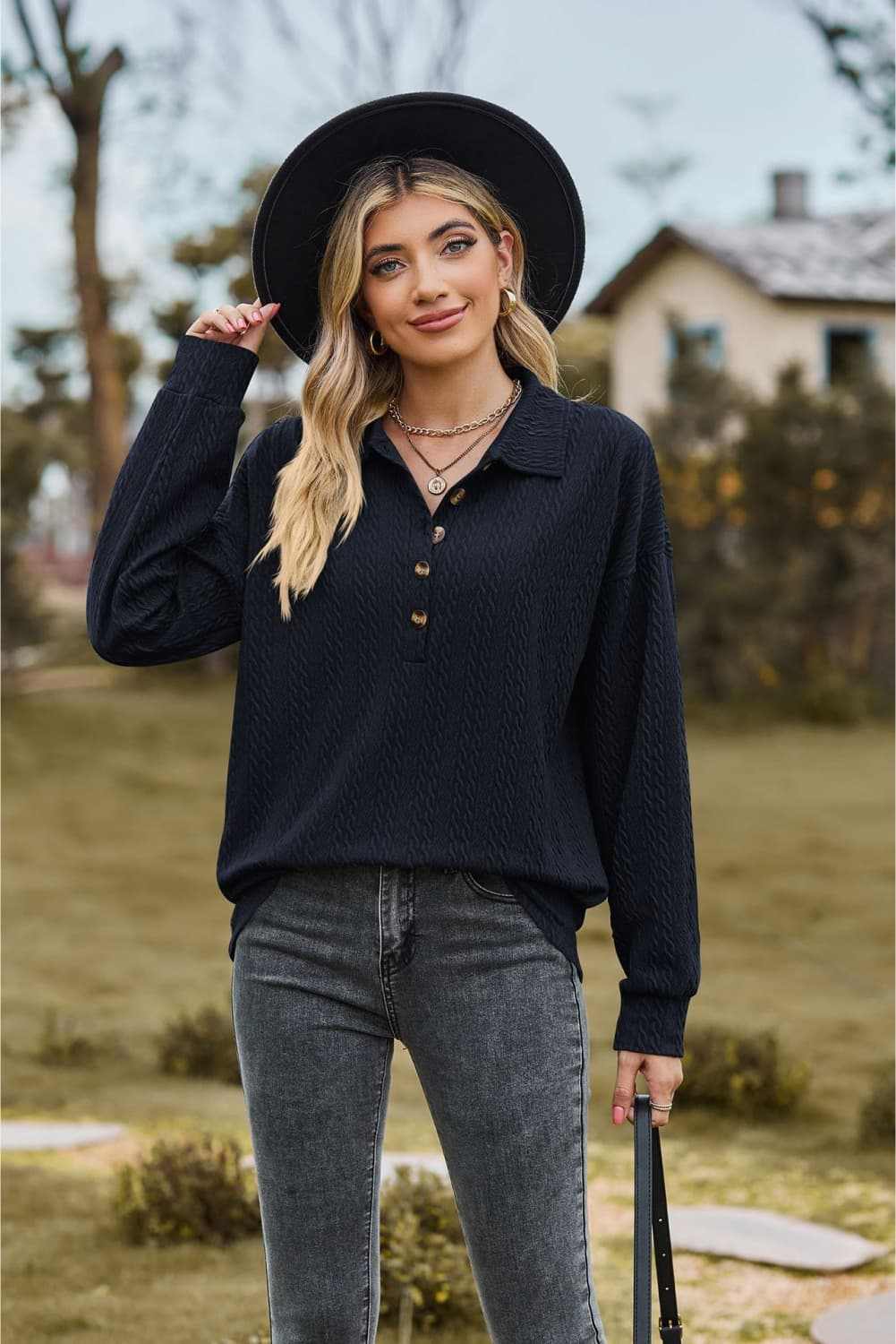Woman wearing black collared neck long sleeve blouse with buttoned detail and casual fit outdoors