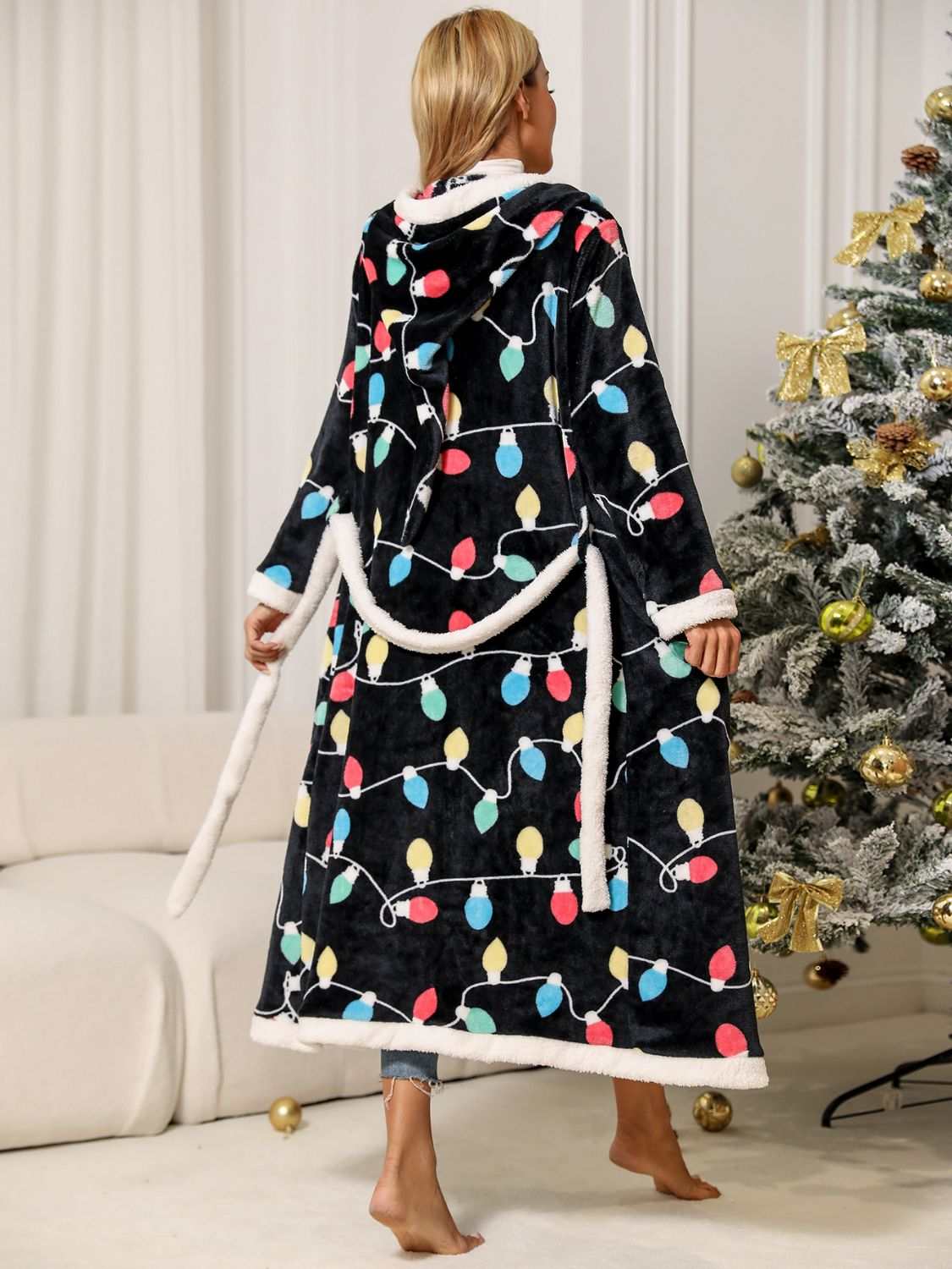 Tie Waist Hooded Robe with festive light pattern, polyester material, long sleeves, tie belt, worn by a person facing a Christmas tree.