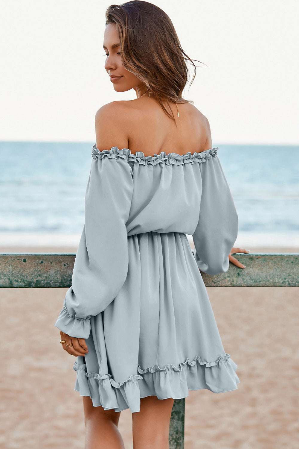 Frill off-shoulder flounce sleeve dress in blue on beach background.