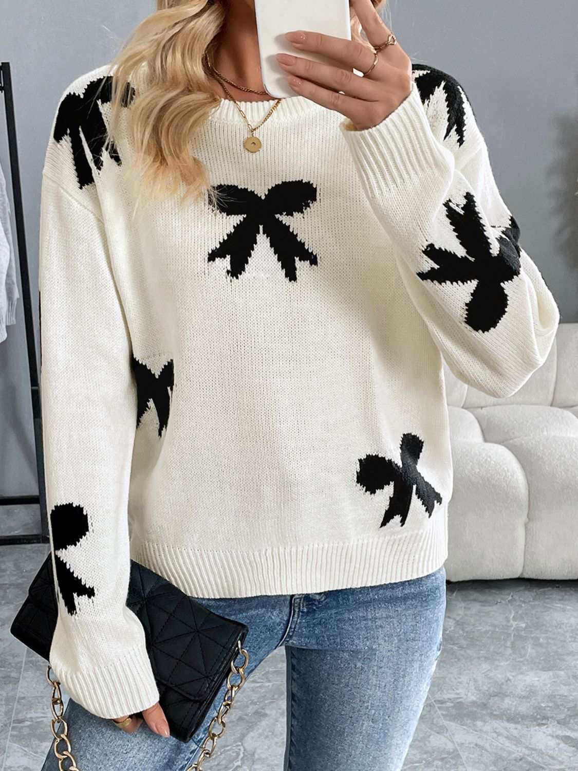 Perfee Bow Graphic Round Neck Long Sleeve Sweater in white with black bow design, moderate stretch, acrylic material.