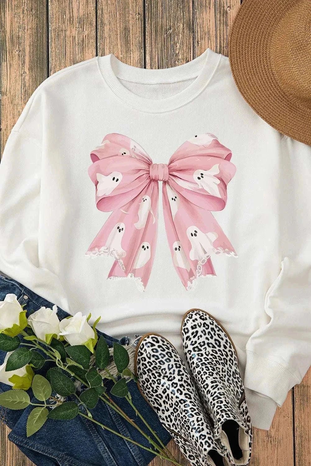 Bow round neck long sleeve sweatshirt with pink bow and ghost design on white fabric.