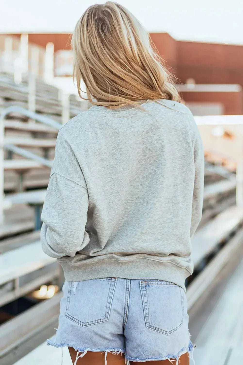 Bow Graphic Round Neck Long Sleeve Sweatshirt on woman outdoors, back view.