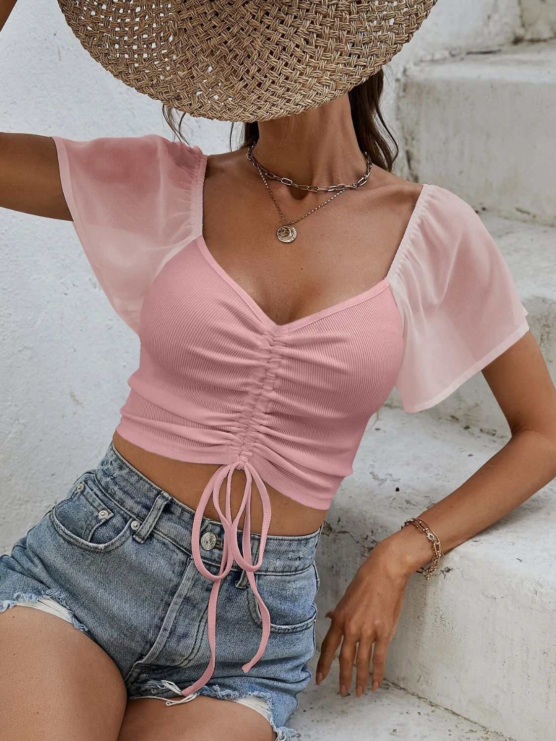Pink drawstring short sleeve crop top paired with denim shorts.