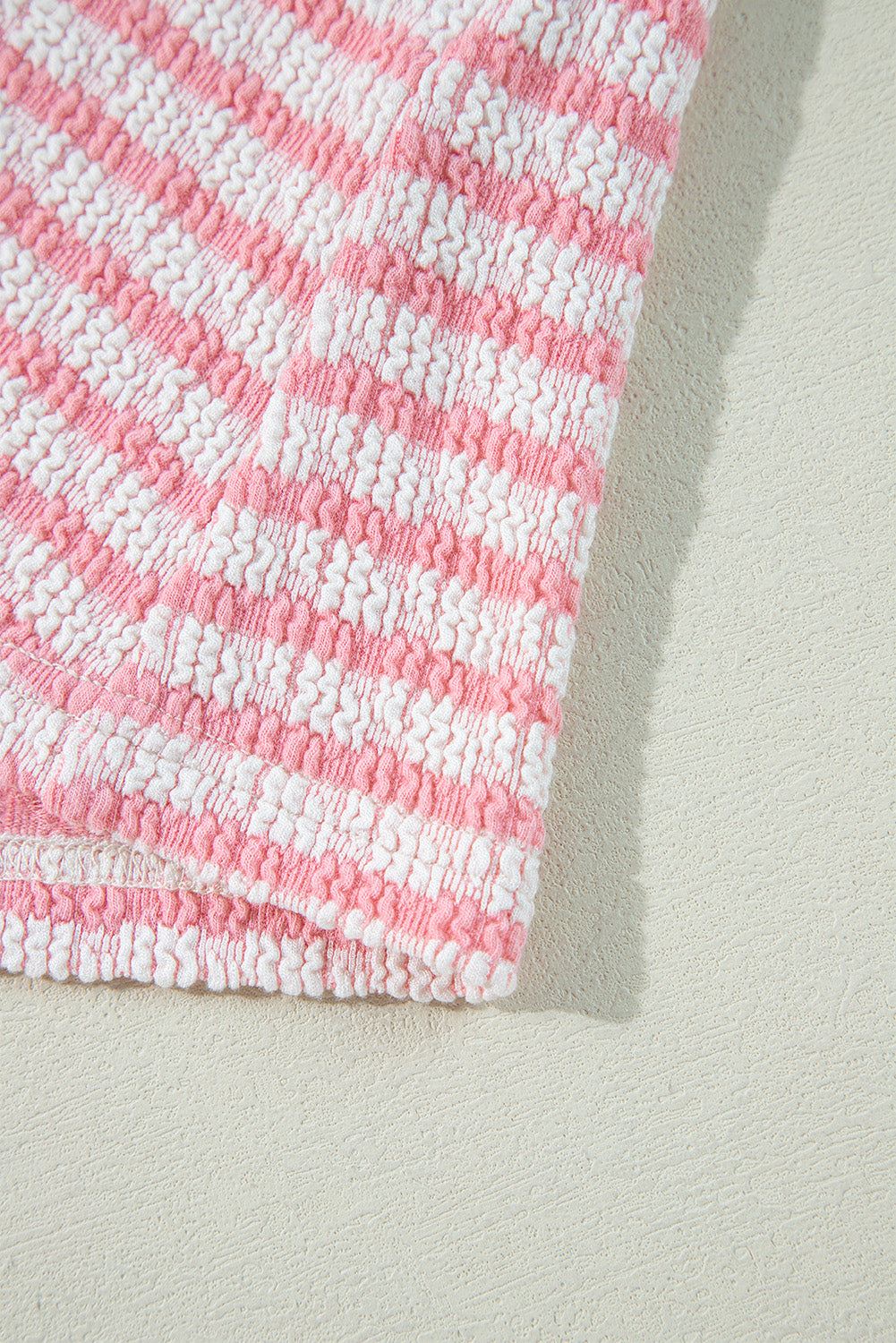 Stripe textured fabric detail of puff sleeve blouse in pink and white.
