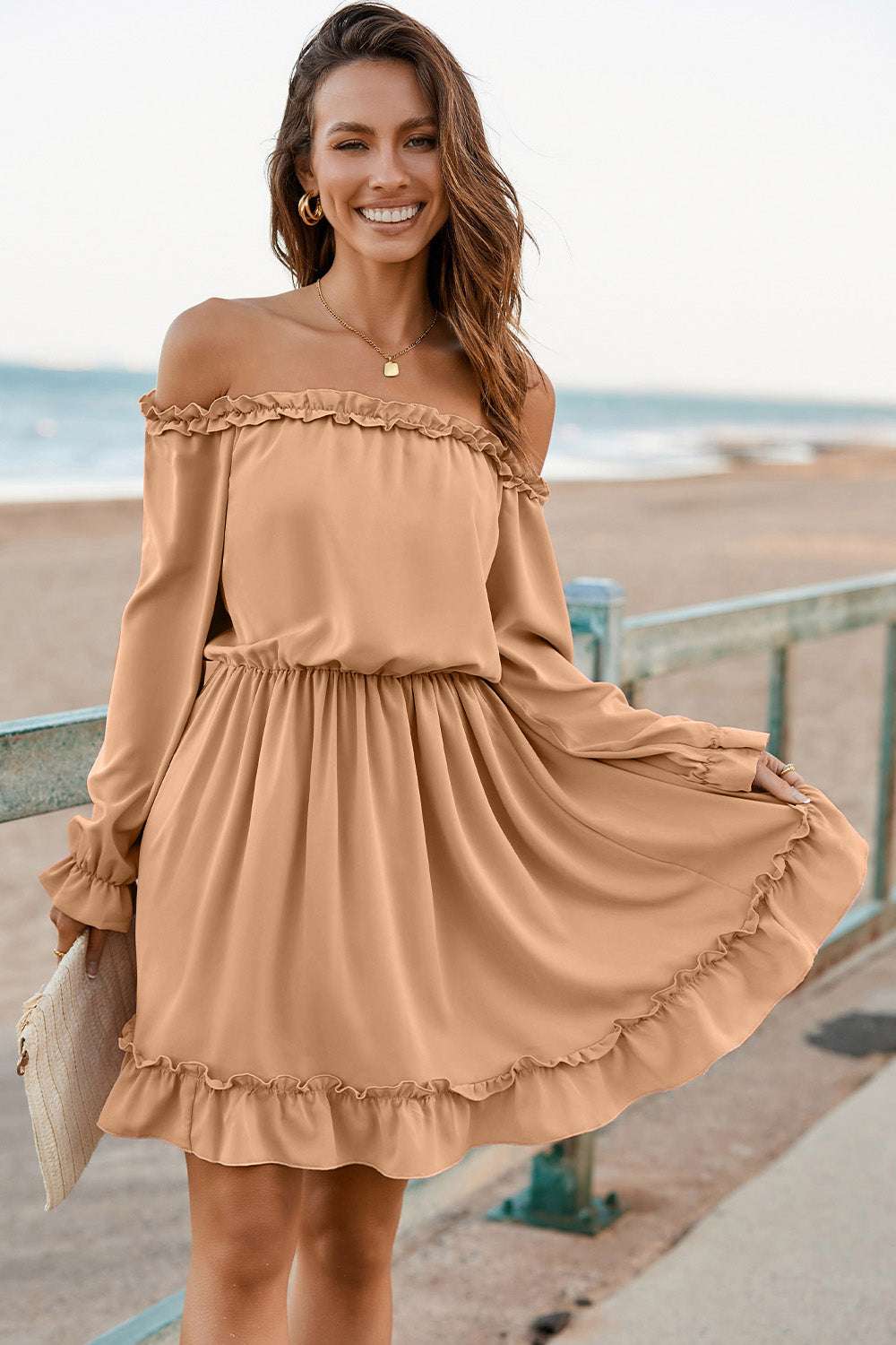 Frill off-shoulder flounce sleeve dress in light brown worn by a woman standing near the beach.
