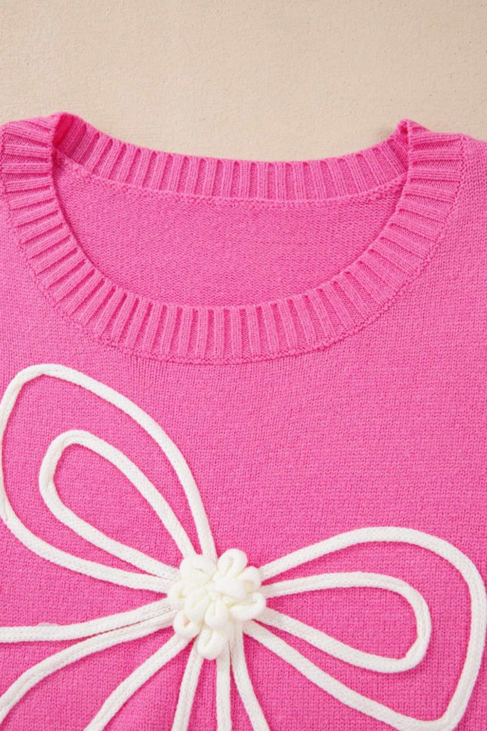 Pink round neck sweater with bow detail and dropped shoulders.