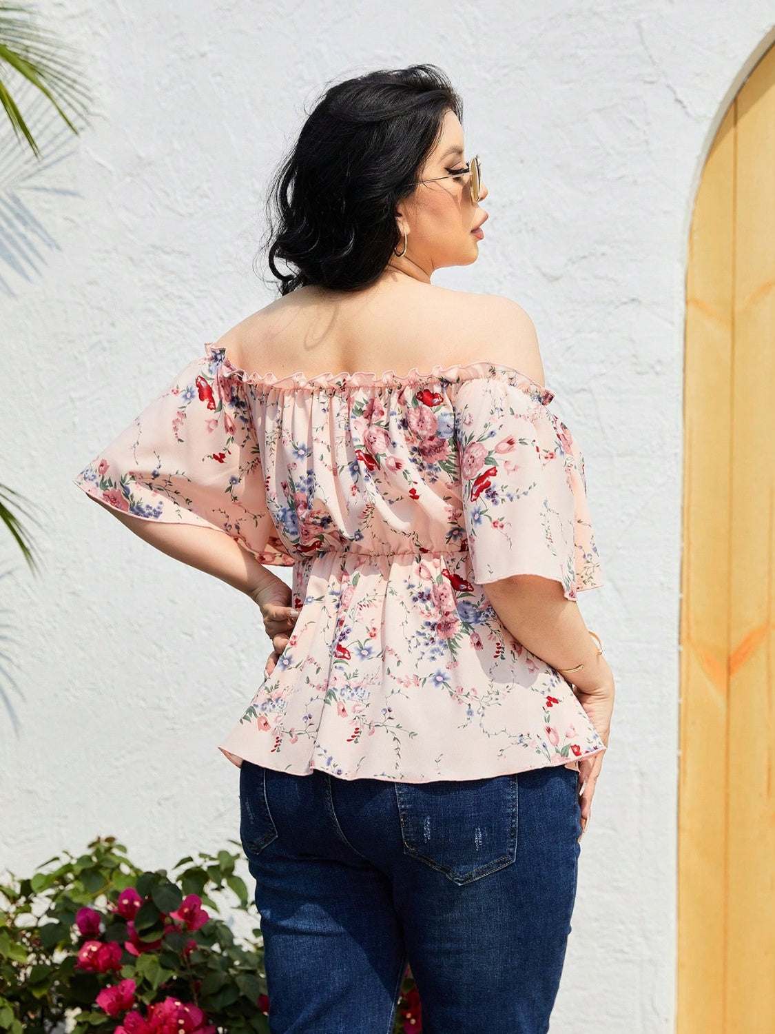 Plus size frill printed flutter sleeve blouse worn outdoors.
