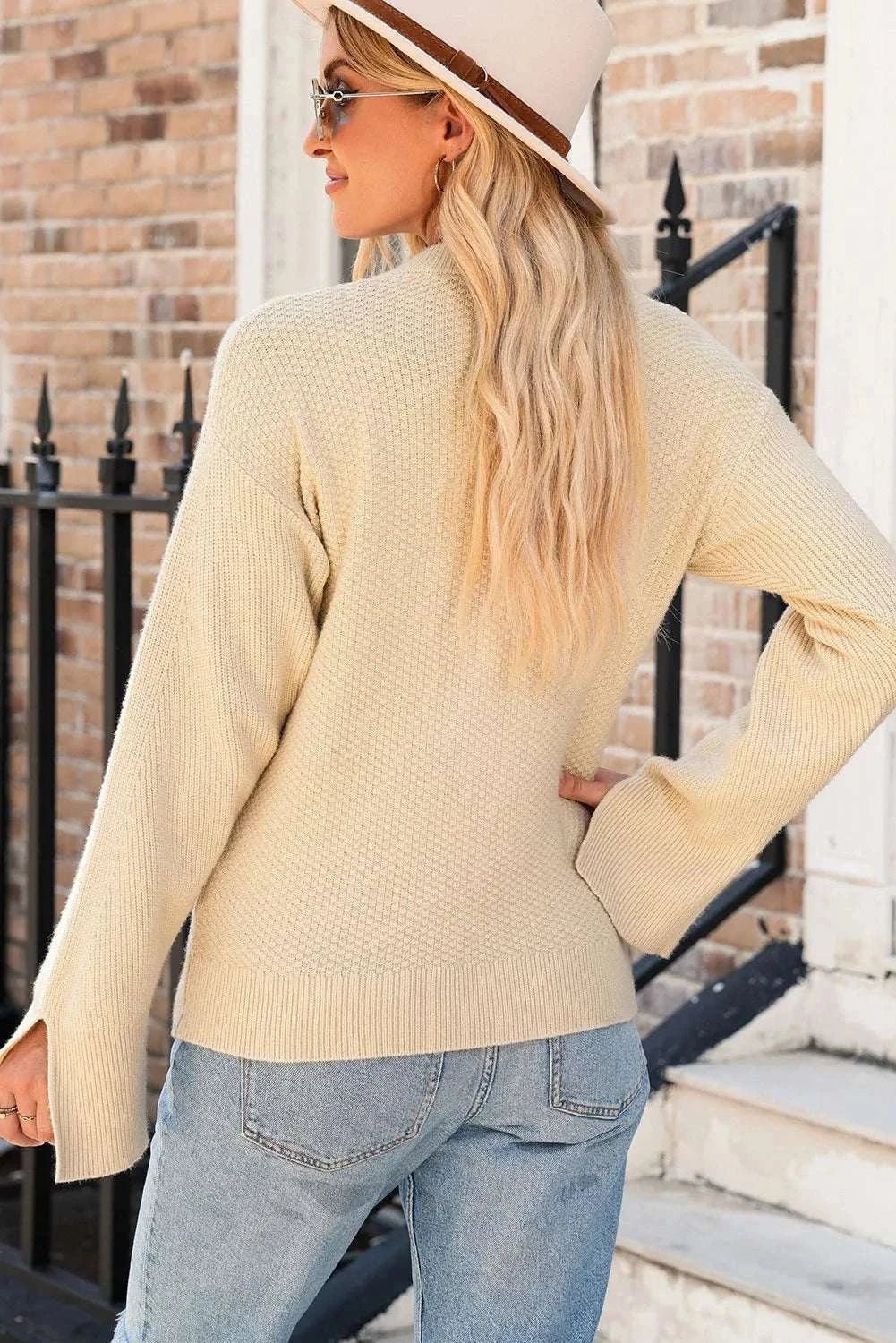 Textured round neck long sleeve sweater with slit design, worn by woman stylishly pairing it with jeans.
