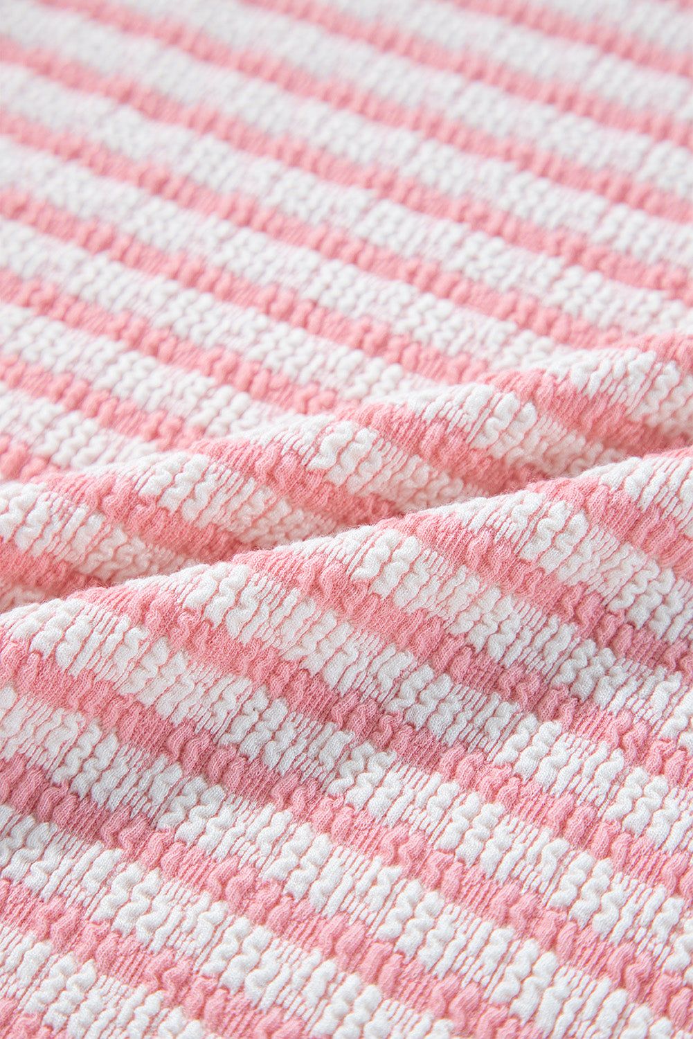 Stripe textured fabric of a puff sleeve blouse in pink and white.