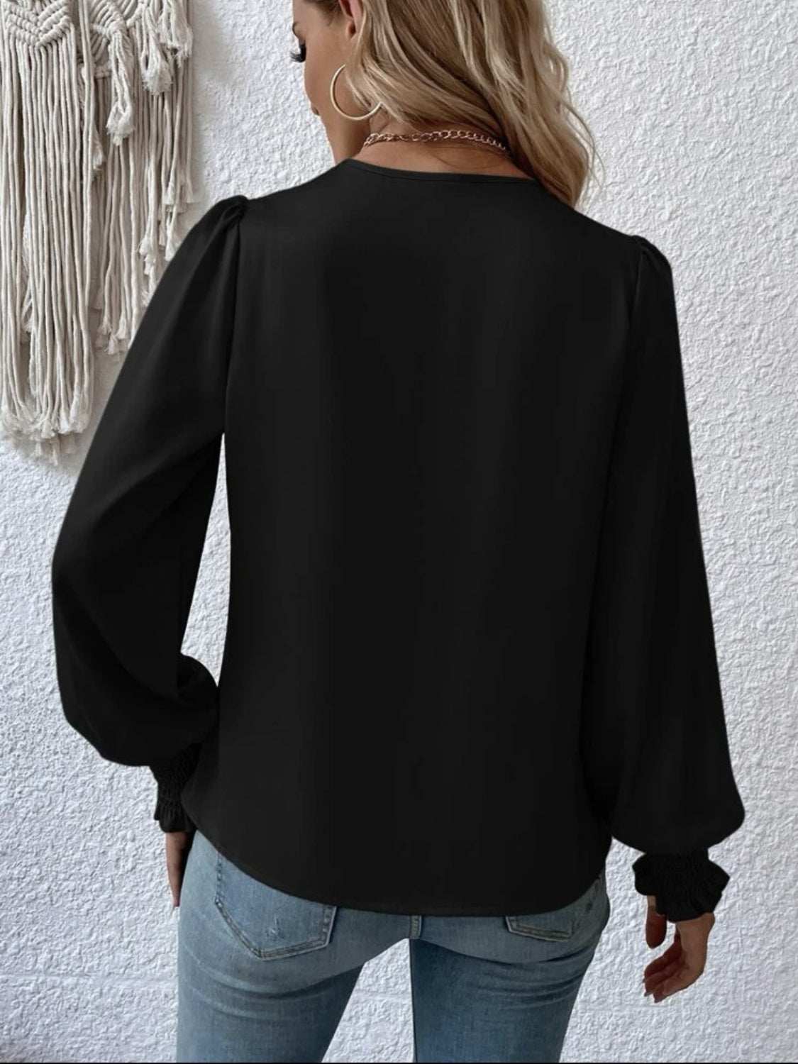 Surplice smocked lantern sleeve blouse in black with opaque, non-stretch polyester fabric.