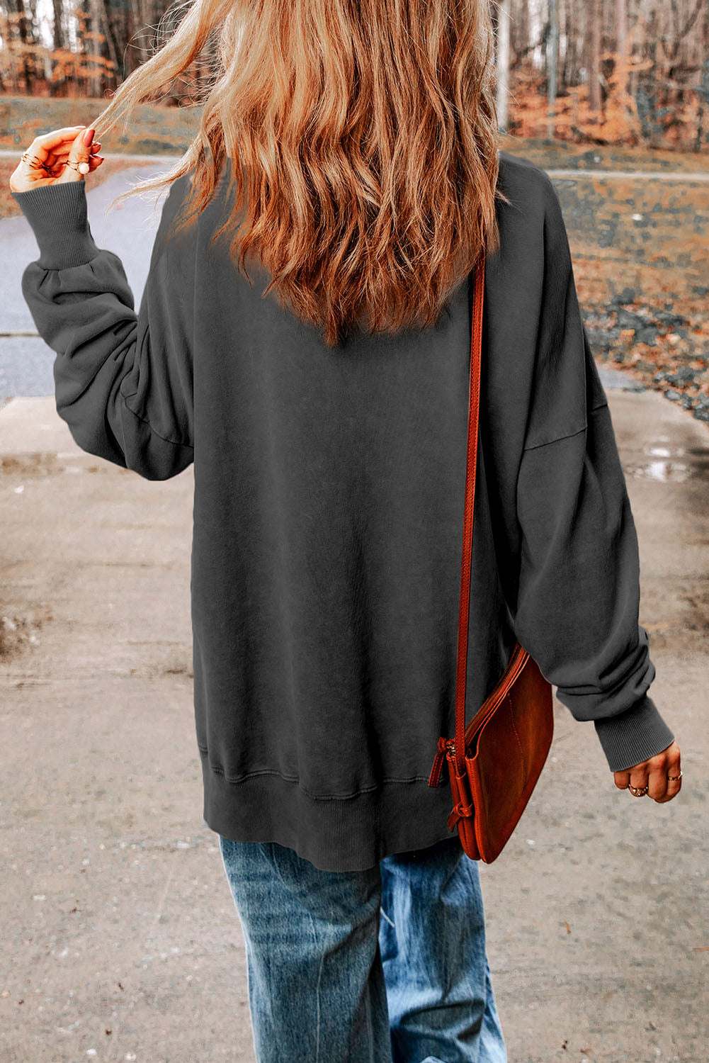 Casual solid-colored round neck long sleeve blouse with dropped shoulders worn outdoors.