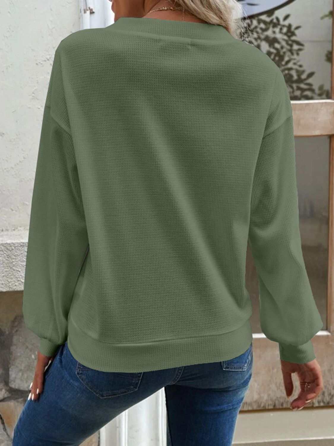 Solid color waffle-knit blouse with V-neck and dropped shoulders, casual style, long sleeves, 100% polyester.