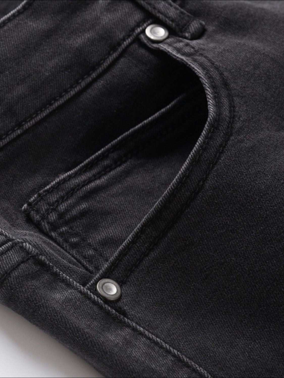 Men's washed bootcut jeans in dark color, close-up of pocket detailing.