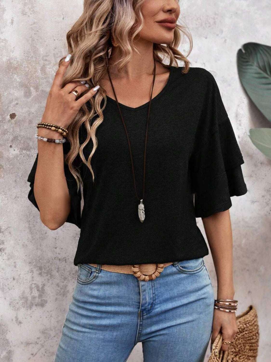 Woman wearing a black V-neck half sleeve blouse with jeans.