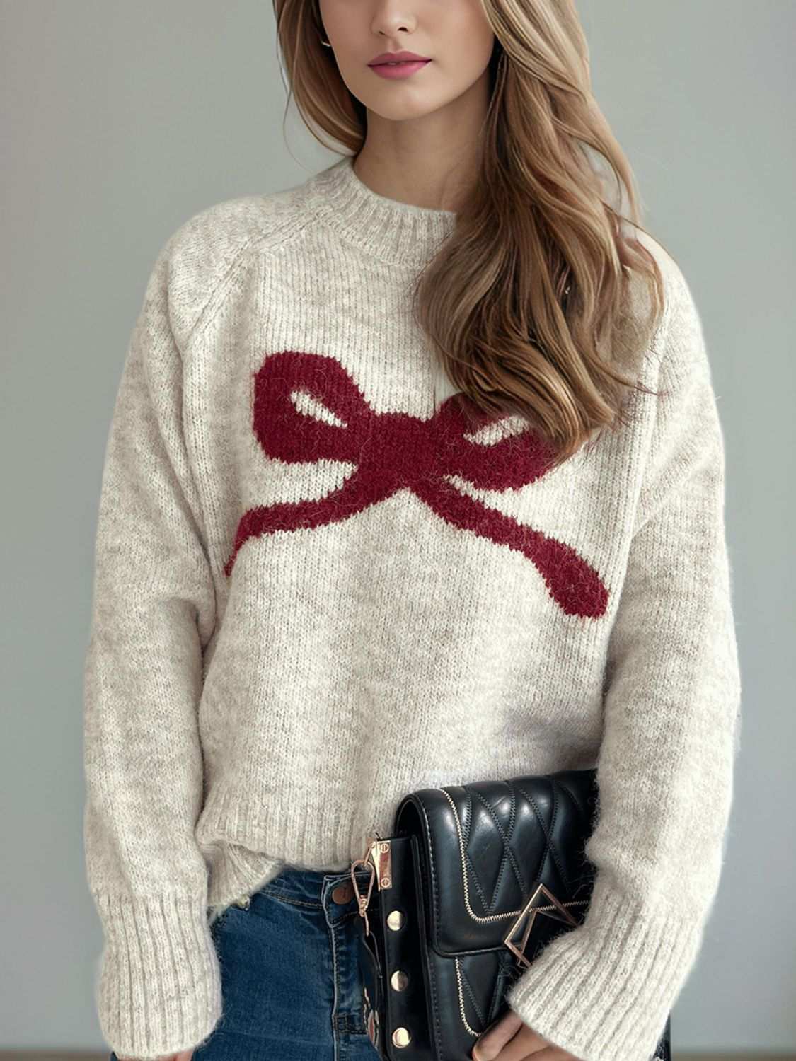 Woman wearing a bow round neck long sleeve sweater with a red bow design.